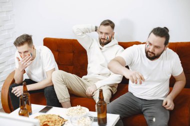 Bir grup taraftar televizyonda bir futbol maçı izliyorlar.