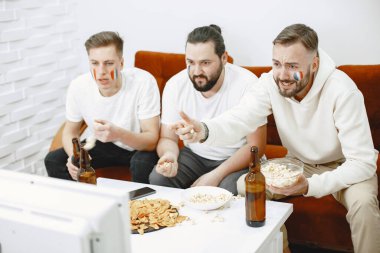 Bir grup taraftar televizyonda bir futbol maçı izliyorlar.