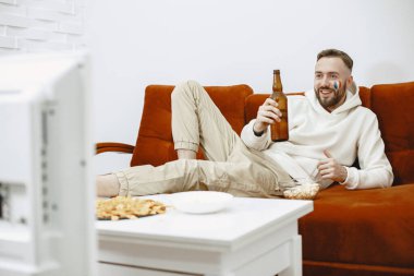 Televizyonda maç izleyen bir adam.