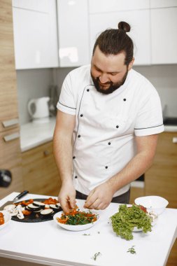 Evde yemek pişiren yakışıklı adam mutfakta salata hazırlıyor.