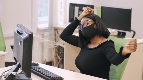 戴面具的非洲年轻妇女在办公室的计算机前工作 — 图库视频影像