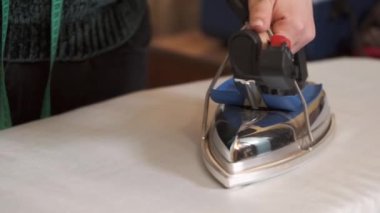 Terzide kumaş ütüleyen kadın.