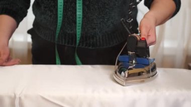 Terzide kumaş ütüleyen kadın.