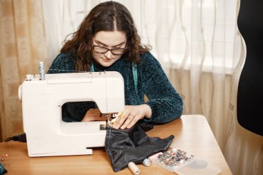 Terzi dikiş makinesi, iplik ve iğne ile elbise dikiyor.