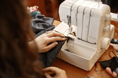 Terzi dikiş makinesi, iplik ve iğne ile elbise dikiyor.