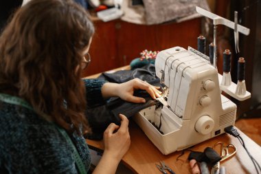 Terzi dikiş makinesi, iplik ve iğne ile elbise dikiyor.