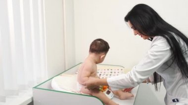 Klinikte bebeği muayene eden kadın doktor.