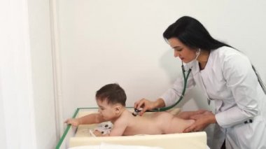 Klinikte bebeği muayene eden kadın doktor.