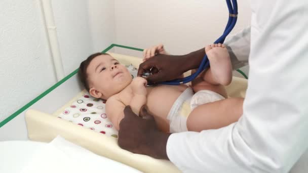 Pediatra médico negro masculino examinando al bebé en la clínica — Vídeos de Stock