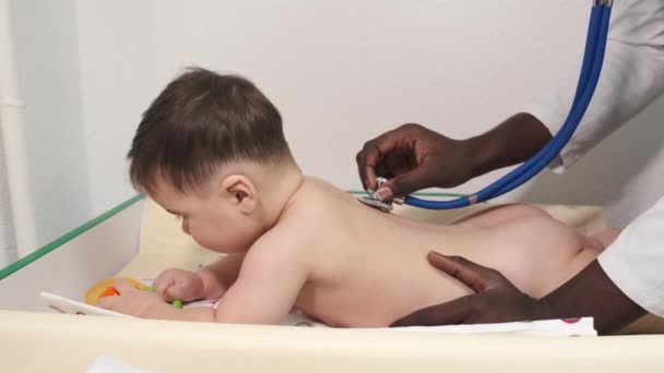 Чоловічий чорний лікар педіатр, який вивчає дитину в клініці — стокове відео