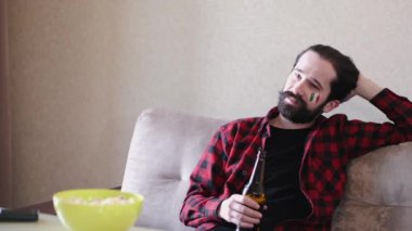 Evde futbol maçı izleyen sakallı adamın portresi.