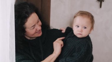 Yaşlı kadın küçük torunuyla evde oynuyor.