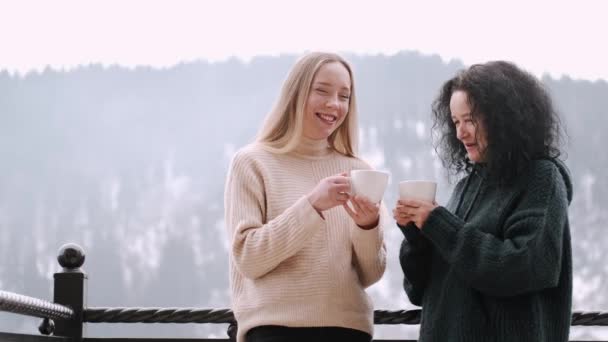 Мать и красивая дочь пьют кофе на балконе с горным пейзажем — стоковое видео