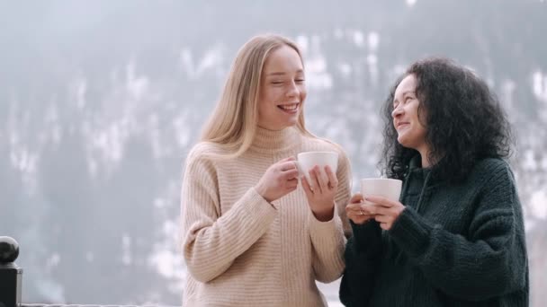 Anne ve güzel kız dağların manzaralı bir balkonda kahve içiyorlar. — Stok video