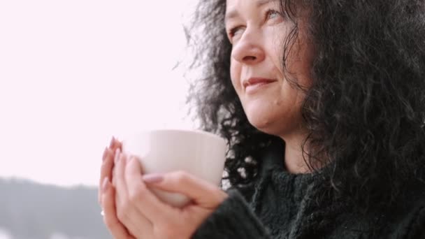 Femme d'âge moyen avec cheveux bouclés boire du café sur le balcon de l'hôtel de montagne — Video