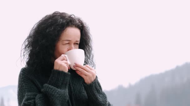 Mujer de mediana edad con cabello rizado beber café en el balcón del hotel de montaña — Vídeo de stock