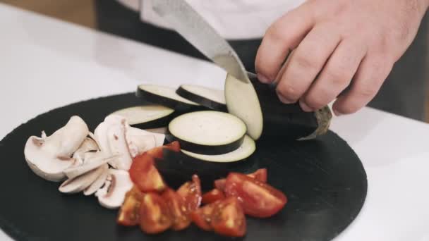 Kok in uniform snijden aubergine voor soep in moderne keuken — Stockvideo