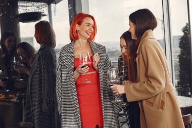 Mutlu kadın arkadaşlar kırmızı şarap içip terasta gülüyorlar.