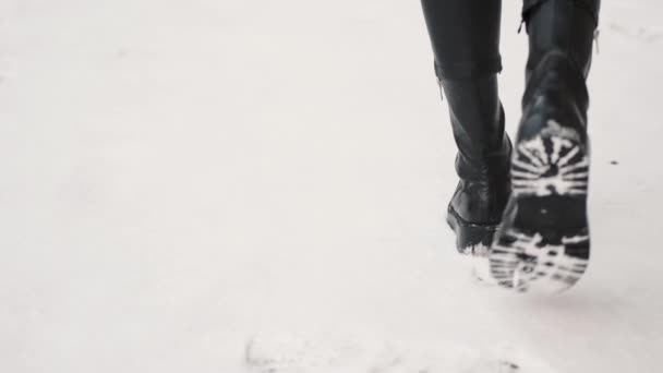 雪の地面に行く革のブーツの女性の足の閉じるアップ — ストック動画