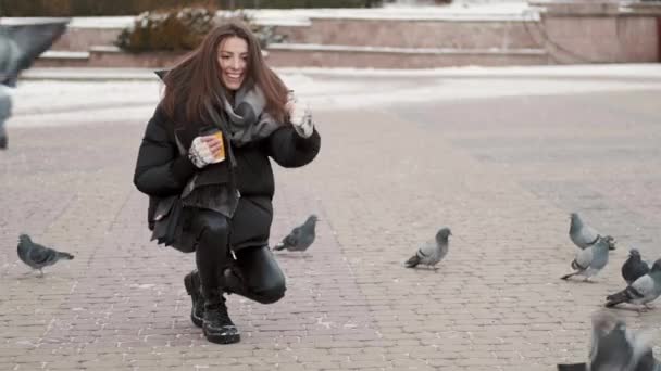 Ung kvinna i elegant bär och kaffe för att gå mata duvor i vinterstaden — Stockvideo