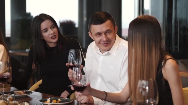 Schöner Mann mit zwei jungen Frauen beim Essen in einem Restaurant — Stockvideo