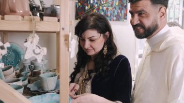 Orta yaşlı eşler çömlek atölyesinde birbirlerine sarılıyorlar.