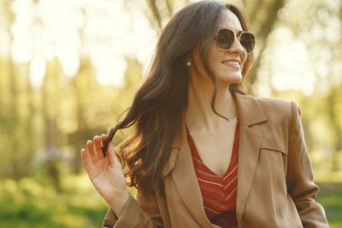 Şık bir kadın bahar parkında vakit geçiriyor.