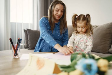 Anne ve kızı evde bir resim çiziyor.
