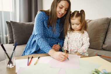 Anne ve kızı evde bir resim çiziyor.