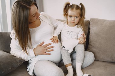 Anne ve kızı kanepede oturuyor.