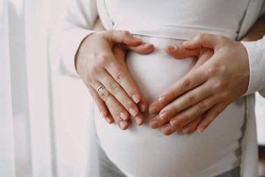 Elleri hamile bir kadının karnında