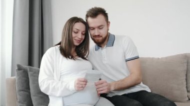 Kocası, sıcak bir odada oturan hamile karısına sarılıyor.