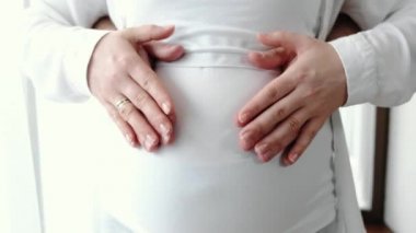 Kocası, sıcak bir odada oturan hamile karısına sarılıyor.