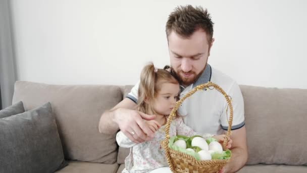 Family of three painting eggs sitting on couch on Easter — Stock Video