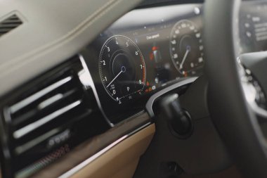 Siyah araba kullanan adam hız göstergesine bakıyor.