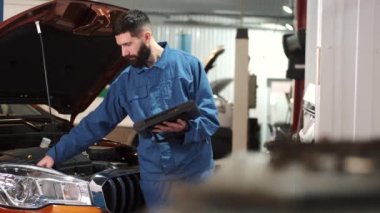 Profesyonel oto tamircisi araba motorunu inceliyor, kaputun altına bakıyor.