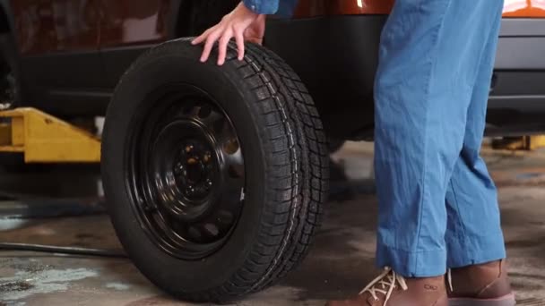 Mecánico sosteniendo un neumático en el garaje de reparación — Vídeos de Stock