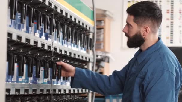 Männlicher Mechaniker in Uniform wählt vor Autolack die richtige Sprühfarbe — Stockvideo