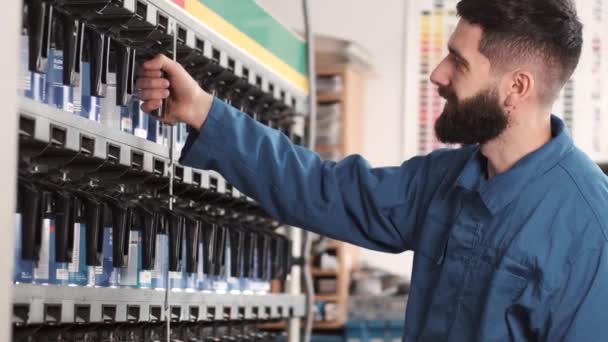 Male mechanic in uniform choosing right spray color before car paint — Stock Video