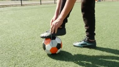 Ayakkabı bağcığı bağlayan çizmeli futbolcu.