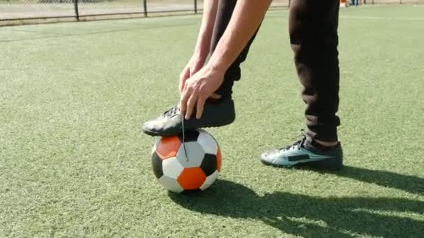 Fotbalista fotbalista v botách vázání tkaničky na hřišti