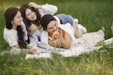 Bir grup kız parkta kitap okuyor.