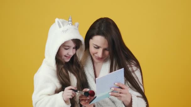 Мать и дочь в халатах делают макияж — стоковое видео