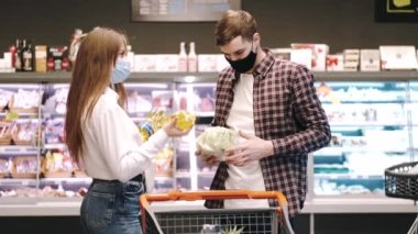 Koruyucu maskeli bir çift süpermarketten alışveriş yapıyor.