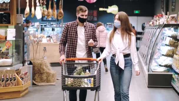 Ζευγάρι με προστατευτικές μάσκες ψωνίζουν στο σούπερ μάρκετ. — Αρχείο Βίντεο