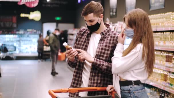 Пара в захисних масках роблять покупки в супермаркеті — стокове відео