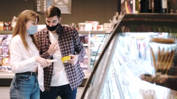 Ζευγάρι με προστατευτικές μάσκες ψωνίζουν στο σούπερ μάρκετ. — Αρχείο Βίντεο