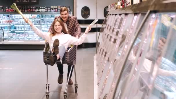 Boldog férfi lovagol a barátnőjével a bevásárlókocsiban — Stock videók