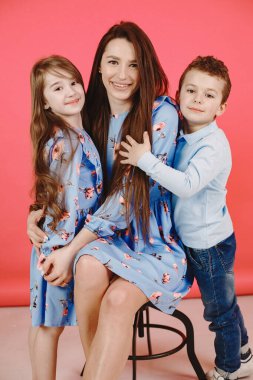 Kırmızı arka planda kızı ve oğlu olan bir anne.