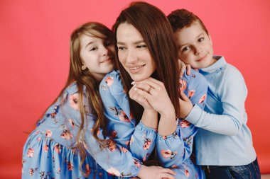 Kırmızı arka planda kızı ve oğlu olan bir anne.